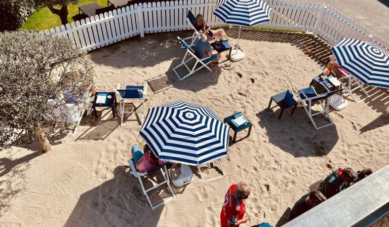 a group of people sitting in chairs and umbrellas in sand