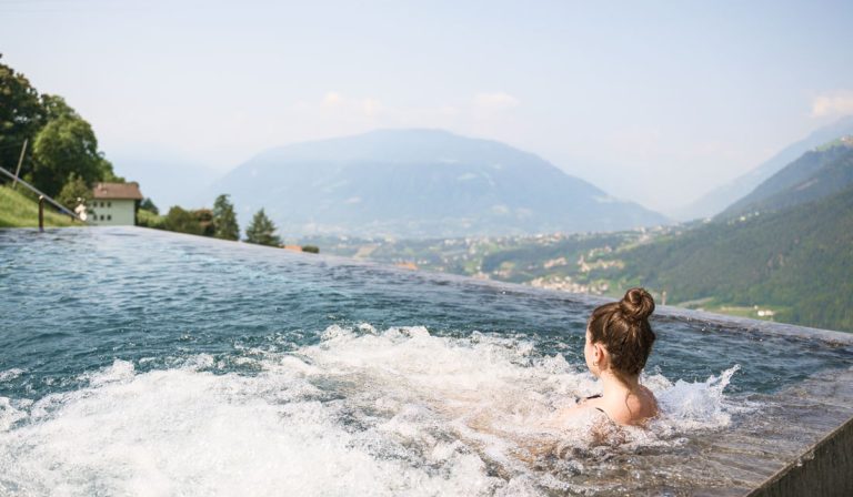 a woman in a pool with a view of a mountain and trees