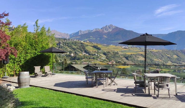 a patio with chairs and umbrellas on a deck with mountains in the background