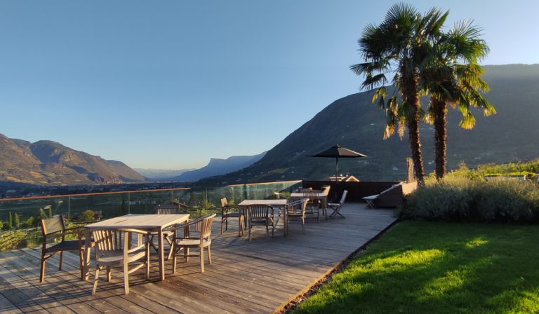 a table and chairs on a deck with a view of mountains and a valley